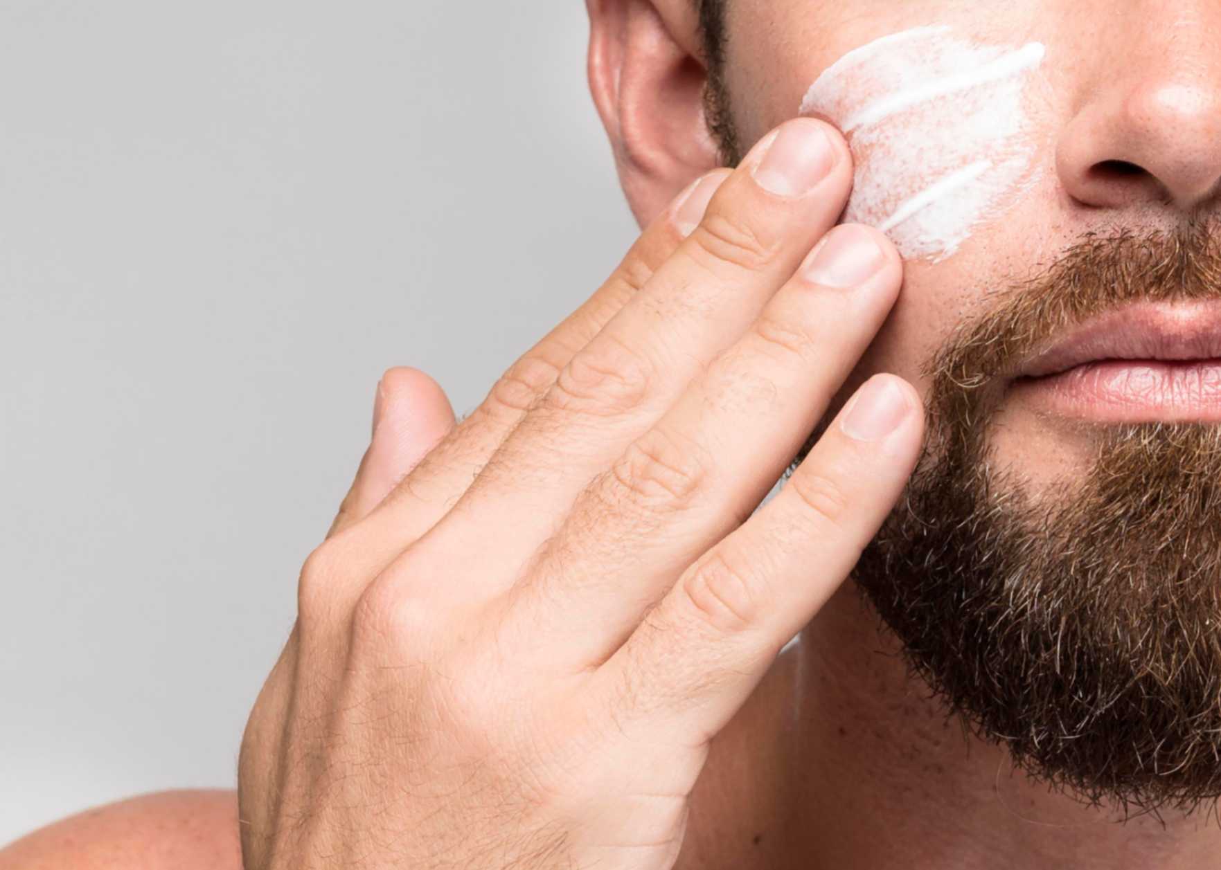 Man applying retinol night cream in bathroom mirror